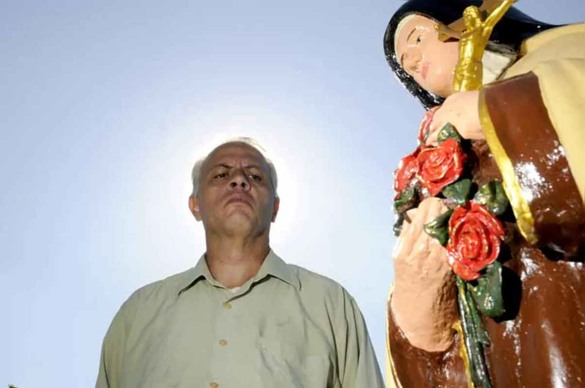 Alexandre Achiropita com uma das estátuas religiosas restauradas por ele no Cemitério São Pedro, em Londrina