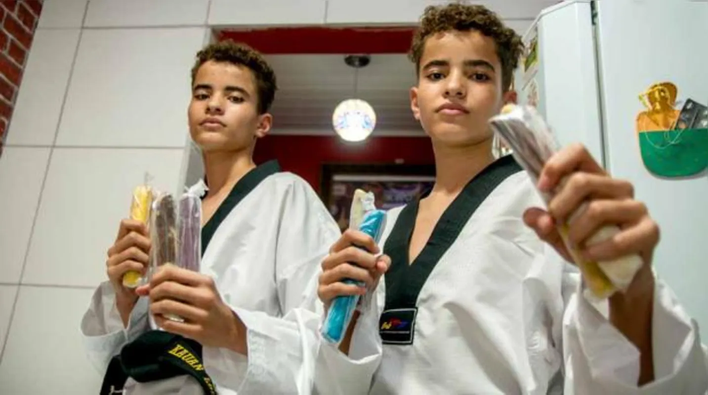 Os gêmeos Kauan e Rhuan dos Santos Lourenço vendem geladinhos para custear as despesas quando participam de competições de taekwondo em outras cidades