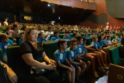 A vice-diretora da Escola Arthur Thomas, Cristiane Tokairin com o público de adultos e crianças presente ao Teatro Ouro Verde para o lançamento do projeto Osquestrando o Futuro