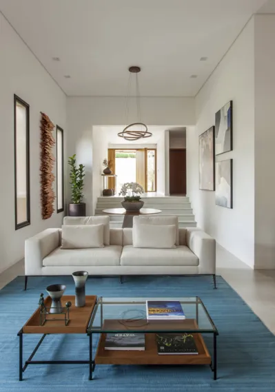 Com o mobiliário marcado pelo minimalismo, o tapete azul claro entra para ‘quebrar’ a paleta clean, ainda assim mantendo a serenidade que pauta todo o cômodo