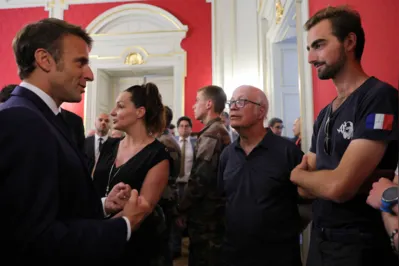 O presidente francês Emmanuel Macron ( conversa com Henri , o jovem de 24 anos conhecido como o 'herói da mochila', que sofreu pequenas facadas ao tentar deter o suspeito em fuga