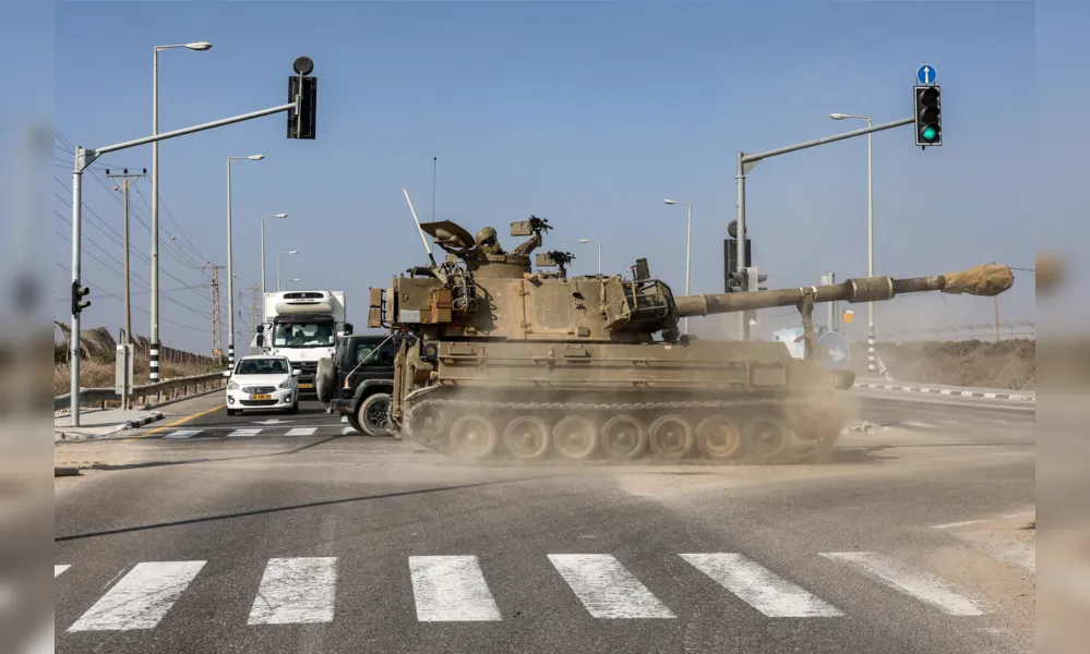 Obus da artilharia israelense atravessa estrada ao longo da Faixa de Gaza onde os combates  se intensificam