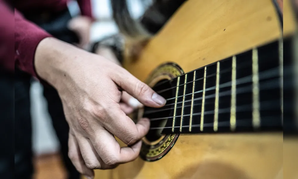 Close-up of a human hand playing guitar indoors