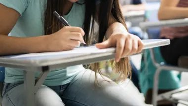 Teenage student writing in the classroom