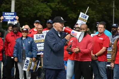 Usando um boné e uma blusa azul com o símbolo da UAW e um megafone na mão, Biden discursou para os trabalhadores
