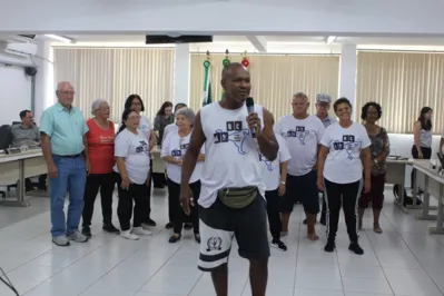 O sócioeducador cultural Edio Elias Gonçalves discursa na sessão da CML, atrás o grupo da melhor idade do projeto A rua dança a cidade apoiado pelo Promic e atua na socialização e atividade física de crianças, jovens e adultos