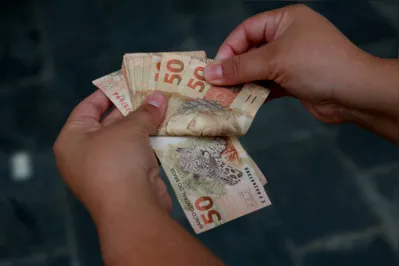 salvador, bahia / brazil - february 25, 2015: hands hold fifty reais (R $ 50.00) bills in the city of Salvador."n"n"n"n"n