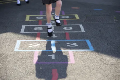 Schoolgirl playing hopscotch in the playground. Only seen from below the waist