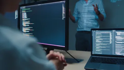Closeup young Asian man software developers mentor leader manager talking to executive team analyzing source code in office at night. Programmer development concept.