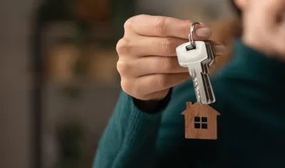 Close up focus on keys, smiling woman Real Estate Agent selling apartment, offering to client, showing at camera, holding documents, contract, making purchasing deal, real estate agent, mortgage or rent