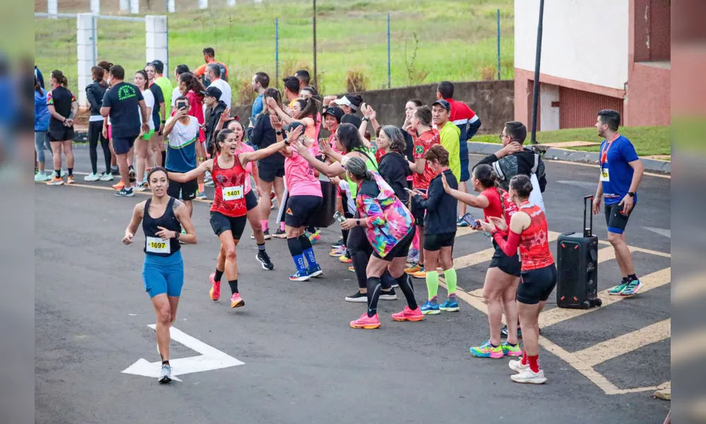 Natalia Melo Couga Rosa, de vermelho, acenando, é fundadora  da marca Caramelo, uma referência em camisetas e acessórios de corrida