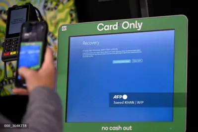 A man takes a picture of the blue screen at self-checkout terminals of a supermarket in Sydney on July 19, 2024. A large-scale outage wrought havoc on IT systems across Australia, with the country's national broadcaster, its largest international airport and a major telecommunications company reporting issues. (Photo by Saeed KHAN / AFP)