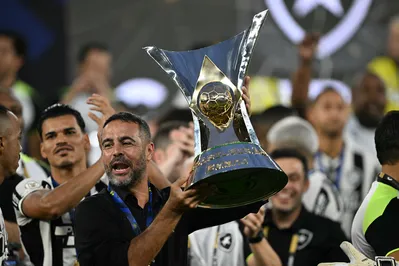 Botafogo's Portuguese head coach Artur Jorge lifts the trophy after winning the championship during the Brasileirao Seria A football match between Botafogo and Sao Paulo at the Nilton Santos Olympic Stadium in Rio de Janeiro, Brazil, on December 8, 2024. A week after lifting its first Copa Libertadores, Botafogo of Rio de Janeiro won the Brazilian football championship on Sunday, ending a league drought of almost thirty years. (Photo by Mauro PIMENTEL / AFP)