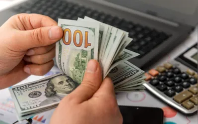 Businessman counting hundreds of dollars at his table