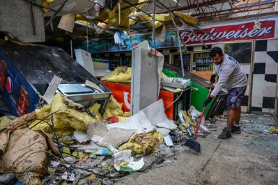 A man cleans debris inside a gas station store in Lakewood Park, Florida, after a tornado hit the area and caused severe damage as Hurricane Milton swept through Florida on October 10, 2024. At least 10 people were dead after Hurricane Milton smashed into Florida, US authorities said, after the monster weather system sent tornados spinning across the state and flooded swaths of the Tampa Bay area. (Photo by GIORGIO VIERA / AFP)