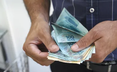 Businessman's hand with Brazilian real notes, creating a loan