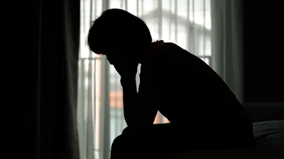 Woman depressed while sitting on bed during day time.