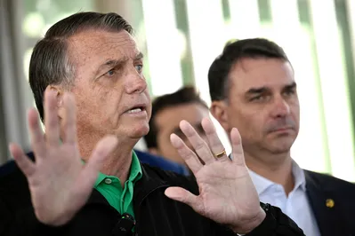 Former Brazilian President Jair Bolsonaro speaks to the press next to his son Senator Flavio Bolsonaro at the Federal Senate in Brasilia on July 17, 2025. A prosecutor asked Brazil's Supreme Court on Tuesday to find Bolsonaro guilty of plotting a coup, in closing arguments after a trial that saw US President Donald Trump try to intervene on behalf of his right-wing ally. (Photo by Mateus Bonomi / AFP)