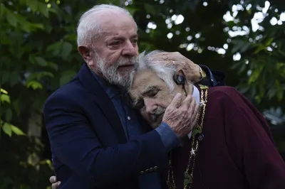 (FILES) Brazil's President Luiz Inacio Lula da Silva (L) embraces former Uruguayan President (2010-2015) Jose Mujica after decorating him with the National Order of the Southern Cross during a visit to the latter's home in Montevideo on December 5, 2024. Uruguay's former president (2010-2015) Jose "Pepe" Mujica, a former guerrilla fighter and icon of the left in Latin America, died at the age of 89 on May 13, 2025, the government announced. The farmer dubbed the "world's poorest president" during his presidency for his modest lifestyle had been diagnosed with cancer of the esophagus in May 2024. (Photo by Dante Fernandez / AFP)
