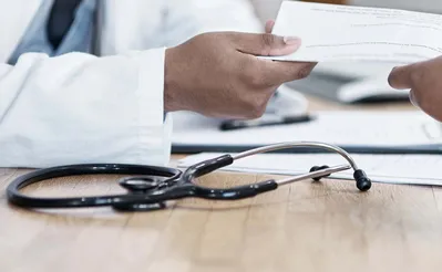 Closeup shot of an unrecognisable doctor giving paperwork to a patient during a consultation
