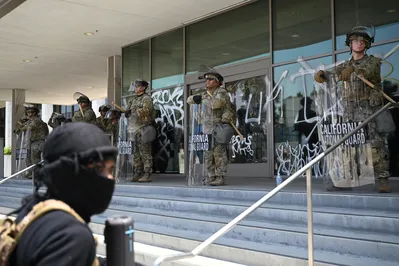 California National Guard members protect the Federal Building, covered in graffiti following protests triggered by immigration raids, in Los Angeles, on June 9, 2025. Police ordered the public to disperse from downtown Los Angeles on June 8 after further unrest, with cars torched and security forces firing tear gas at protesters, in the wake of US President Donald Trump's deployment of National Guard troops to America's second-biggest city. Protests in Los Angeles, home to a large Latino population, broke out on June 6, triggered by immigration raids that resulted in dozens of arrests of what authorities say are illegal migrants and gang members. (Photo by RONALDO SCHEMIDT / AFP)