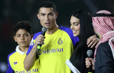 (FILES) Portuguese forward Cristiano Ronaldo (C-L), accompanied by his partner Georgina Rodriguez (C-R) and his son Cristiano Ronaldo Jr (L), greets the crowd at the Mrsool Park Stadium in the Saudi capital Riyadh on January 3, 2023, upon his presentation as an Al-Nassr player. Cristiano dos Santos, the eldest son of five-time Ballon d'Or winner Cristiano Ronaldo, was called up to the Portugal Under-15 squad for the first time on May 6, 2025. The 14-year-old, who, like his father, plays for Al-Nassr in Saudi Arabia, has also had spells with Ronaldo's former clubs Manchester United and Juventus. (Photo by FAYEZ NURELDINE / AFP)