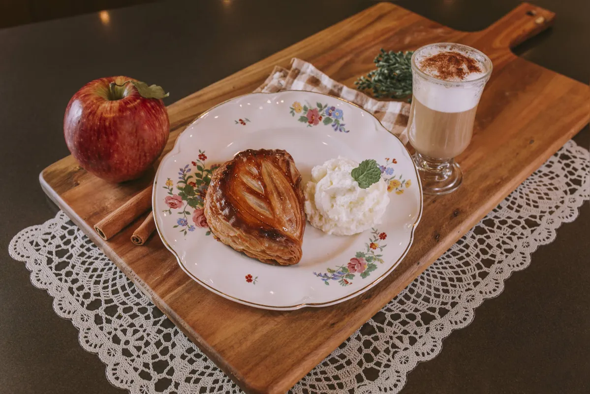 Chausson recheado com maçã e canela servido com chantilly e cappucino, especialidade do Nelson Boulangerie
