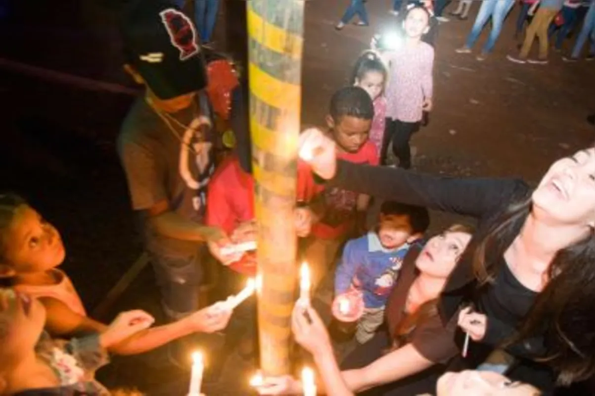 Em cerimônia tradicional da comunidade, mulheres e crianças colam velas para Santo Antônio, o casamenteiro