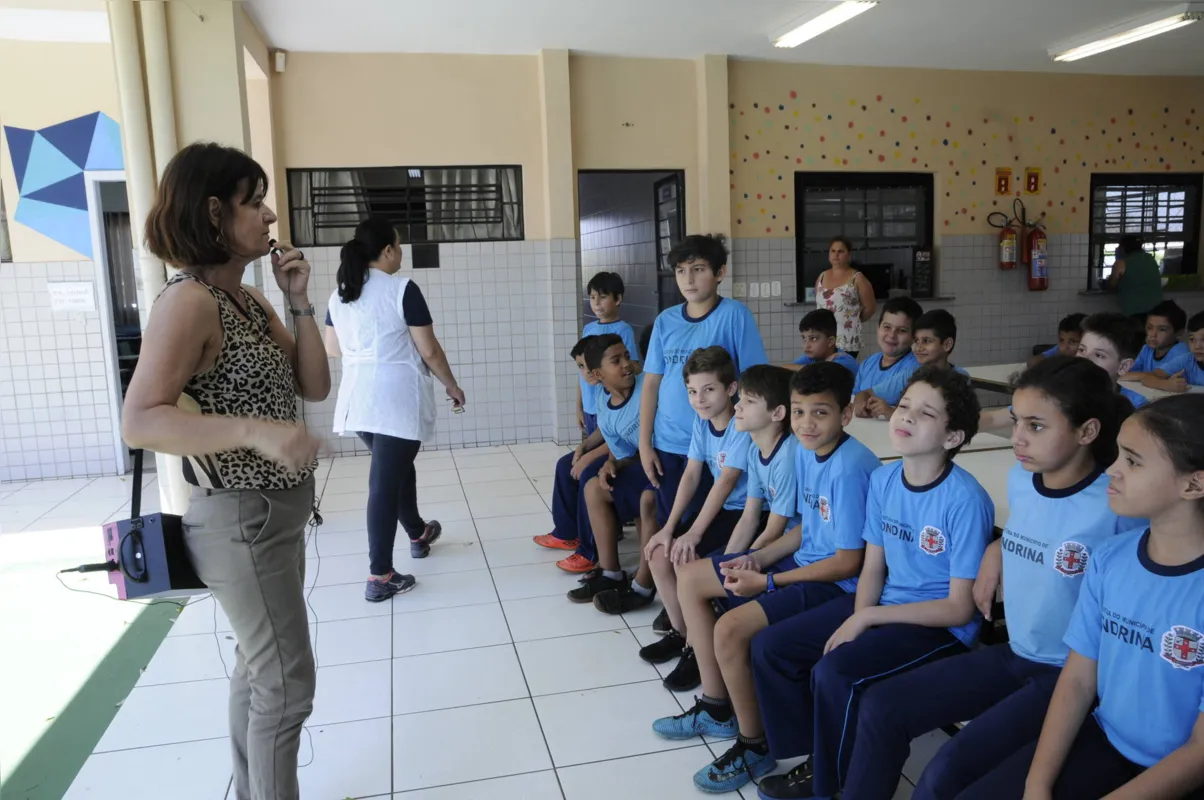 Sandra Regina Alves da Rocha, vice-diretora da Escola Municipal  Roberto Pereira Panico, fala com os alunos usando um microfone e caixa de som