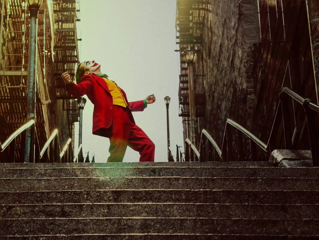Como perturbador ser fantasmagórico, Artur Fleck (Joaquin Phoenix) caminha arrastando seus sonhos de se converter em humorista