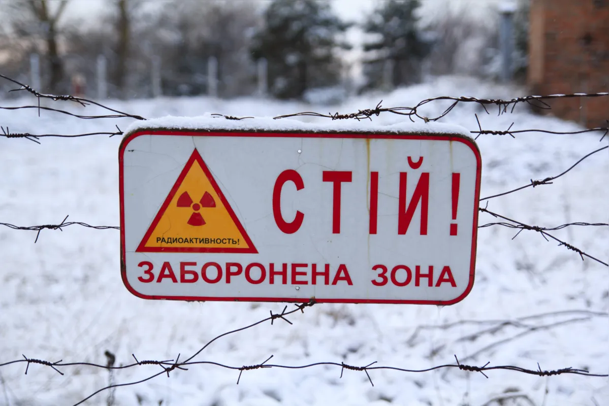 Placa com os dizeres: "Pare! Área restrita por radioatividade" em cerca ao redor da cidade de Chernobil, Ucrania