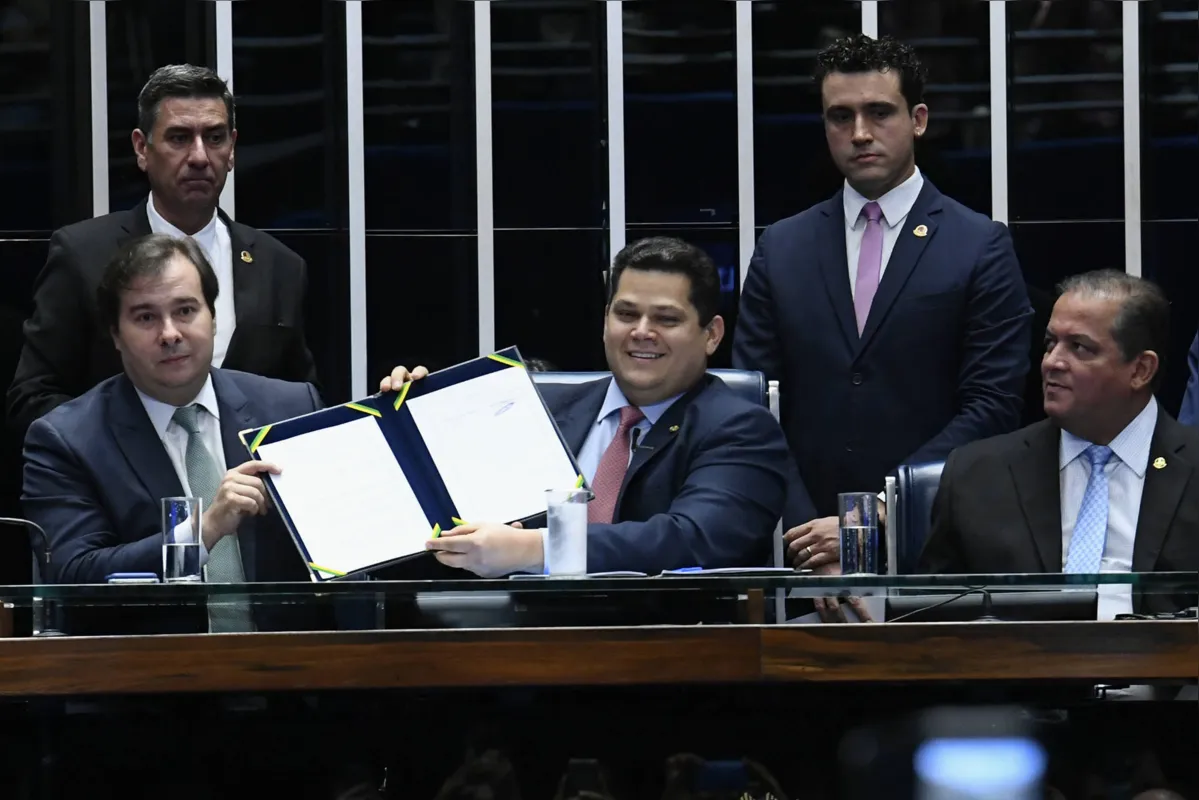 Os presidentes da Câmara dos Deputados, Rodrigo Maia, e do Senado, Davi Alcolumbre, exibem o documento com as novas regras da Previdência