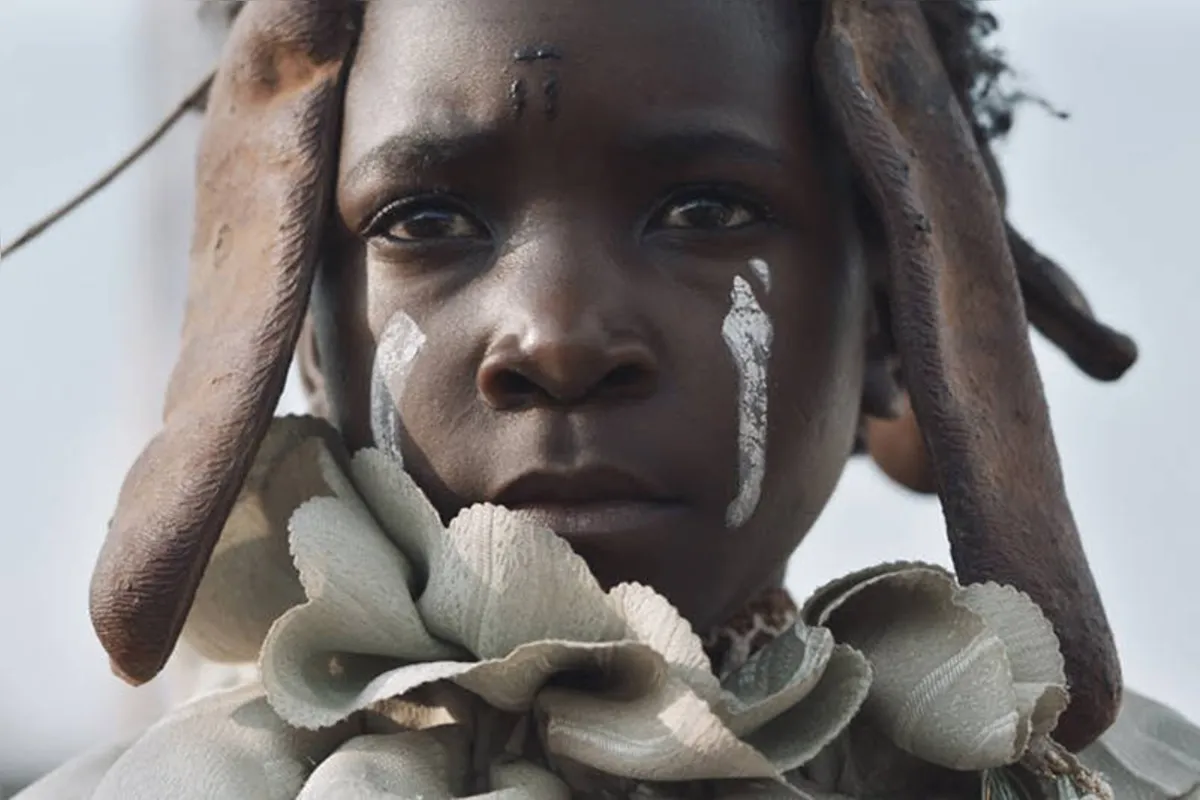 Shula (Margaret Mulubwa) mostra a realidade de mulheres africanas que são presas por bruxaria e tem até mesmo o rosto pintado para fazer selfies de turistas