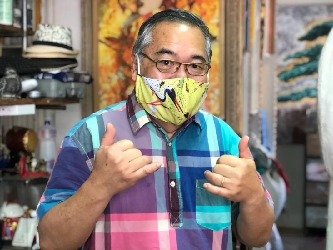 Carlos Kubo com a máscara que tem o tsuru, referência ao belo pássaro que ele recria em várias obras e que simboliza saúde e vida longa 