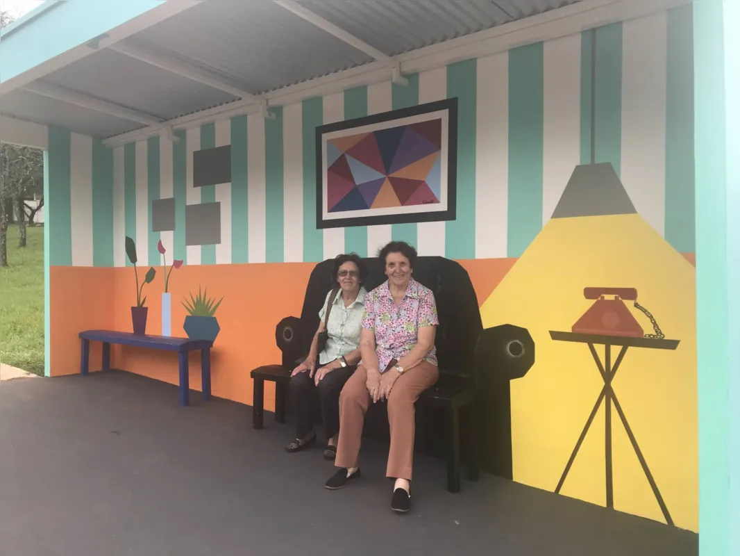 As irmãs Rosa e Antônia Orives 'brincam' de aguardar o ônibus na sala improvisada em plena rodovia