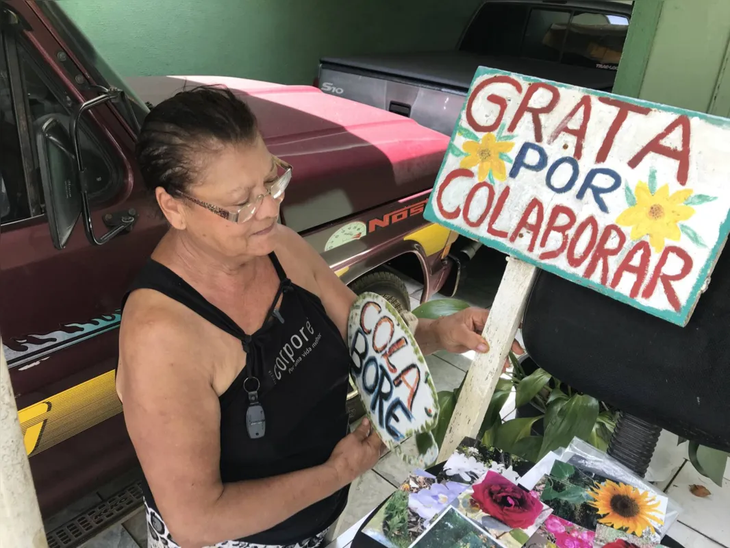 Maria José Tenani com as fotos e placas que sobraram do jardim que fez em área pública na Vila Penteriche