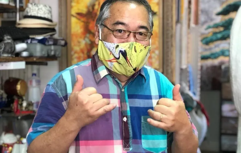 Carlos Kubo com a máscara que tem o tsuru, referência ao belo pássaro que ele recria em várias obras e que simboliza saúde e vida longa 