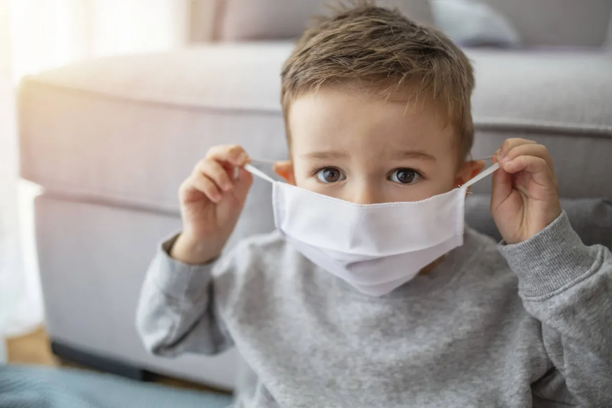 Young child wearing a respiratory mask as a prevention against the Coronavirus Covid-19. Little boy wearing anti virus mask staying at home. Protection against flu and virus infection