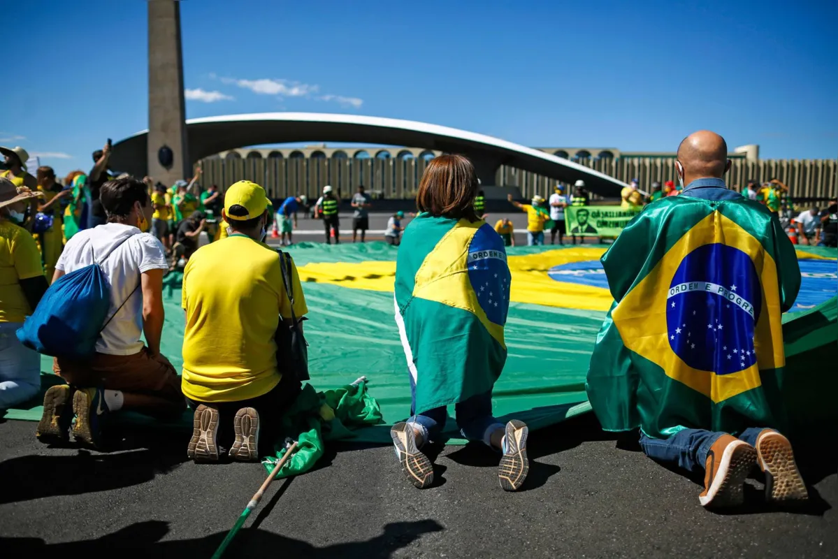 Apoiadores do governo Bolsonaro ajoelham em frente a uma versão gigante da Bandeira do Brasil, em Brasília - Junho de 2020