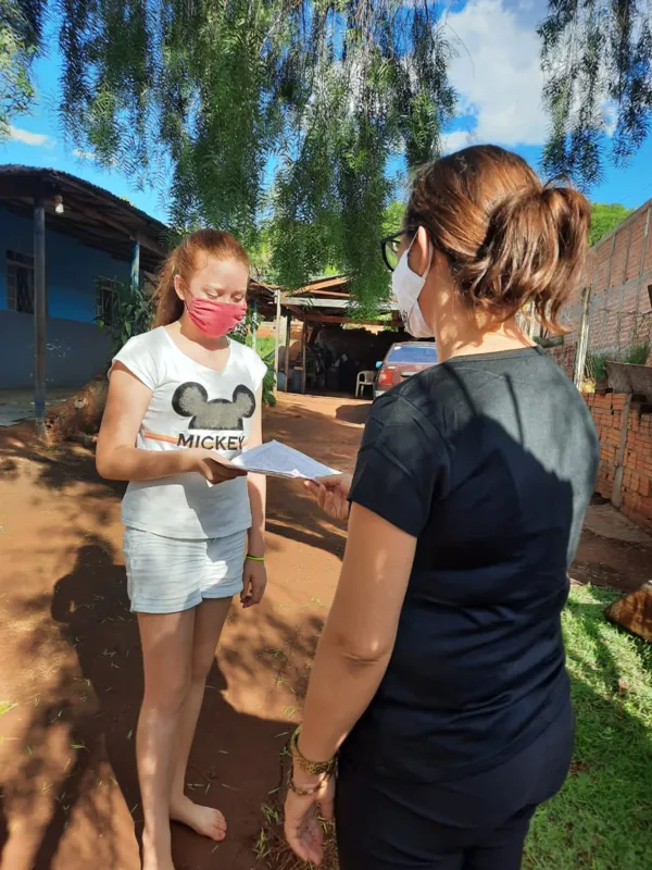 A coordenadora Rosângela Andréa Ulhmann, do Distrito Selva, entrega material na casa da aluna Julia, do 5º ano