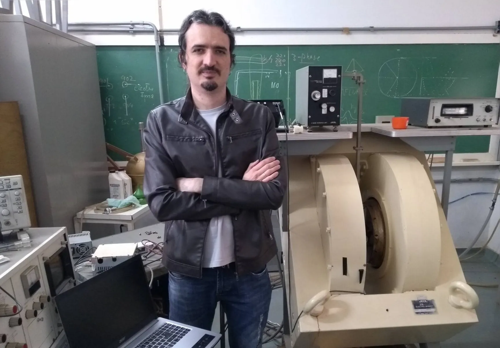 Daniel Farinha Lavezi, ao lado do Espectrômetro de Ressonância Paramagnética Eletrônica, do Departamento de Física da UEL