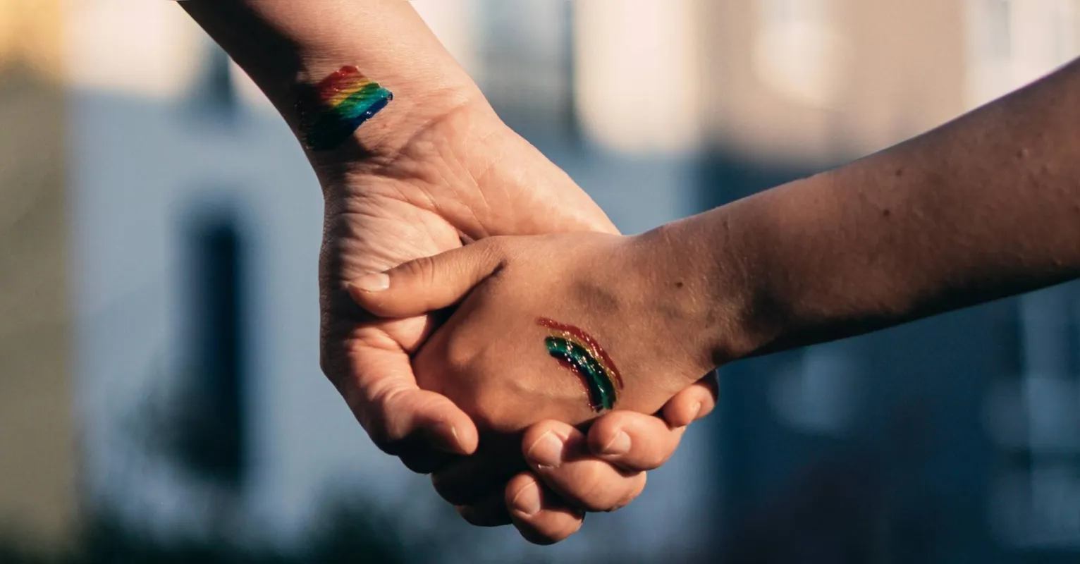 A mother holding hands with her daughter with the colors of diversity in her hands, lgtb concept