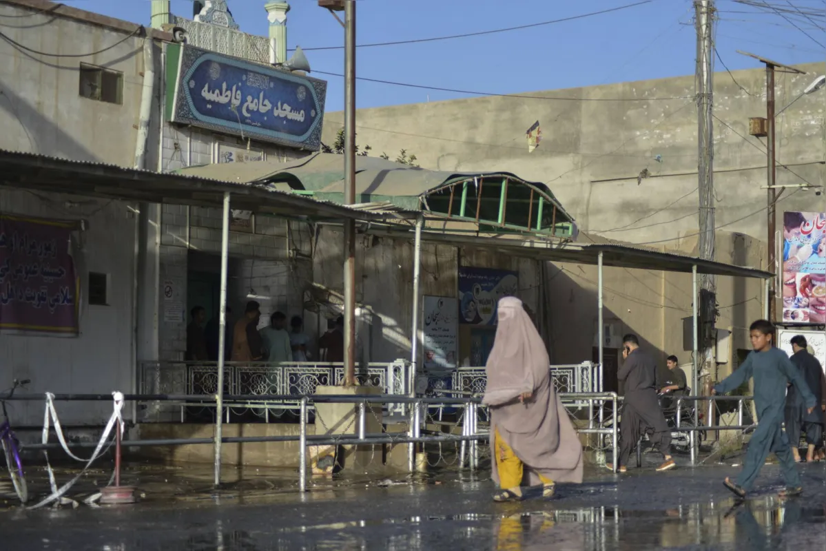 Mulher vestida com burka passa em frente à mesquita alvo de ataque em Kandahar