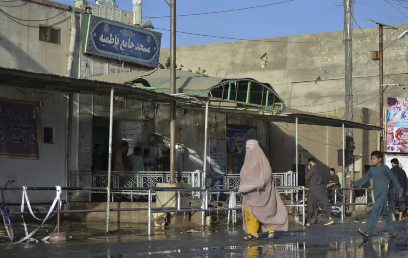 Mulher vestida com burka passa em frente à mesquita alvo de ataque em Kandahar