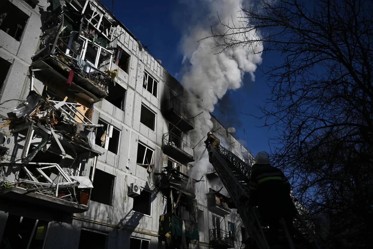 Bombeiros trabalham em um incêndio em um prédio após bombardeios na cidade de Chuguiv, no leste da Ucrânia, em 24 de fevereiro de 2022, enquanto as forças armadas russas tentam invadir a Ucrânia de várias direções