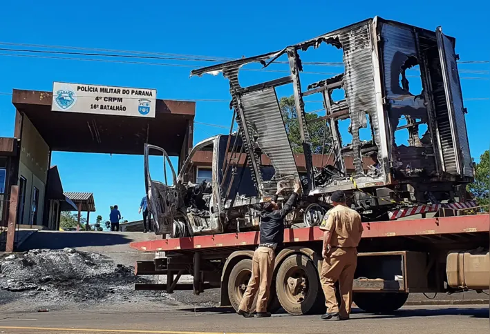 Military police officers check a burnt out truck outside a Military police station in Guarapuava, southern Brazil on April 19, 2022. - Approximately 30 heavily armed criminals attacked a police station and engaged in a fierce gun battle with the police during the early morning on April 18, 2022 during an attempted robbery of a cash-in-transit company that left three people injured. (Photo by Eduardo Matysiak / AFP)