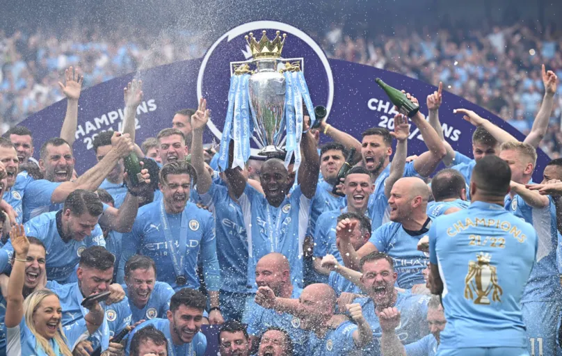 Manchester City's Brazilian midfielder Fernandinho lifts the Premier League trophy as City players celebrate on the pitch after the English Premier League football match between Manchester City and Aston Villa at the Etihad Stadium in Manchester, north west England, on May 22, 2022. - Manchester City won the Premier League for the fourth time in five seasons after a pulsating title race reached a dramatic conclusion as the champions staged an incredible comeback from two goals down to beat Aston Villa 3-2 on Sunday. (Photo by Oli SCARFF / AFP) / RESTRICTED TO EDITORIAL USE. No use with unauthorized audio, video, data, fixture lists, club/league logos or 'live' services. Online in-match use limited to 120 images. An additional 40 images may be used in extra time. No video emulation. Social media in-match use limited to 120 images. An additional 40 images may be used in extra time. No use in betting publications, games or single club/league/player publications. /
