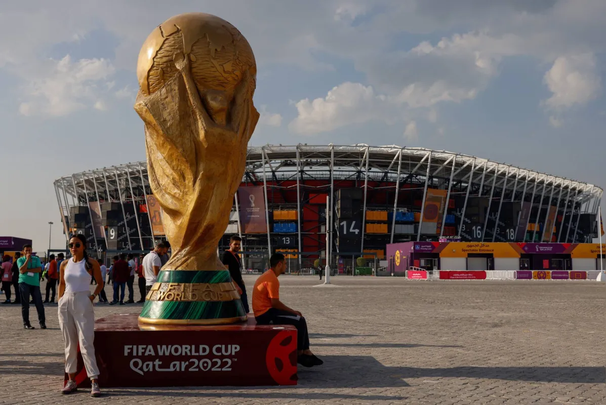 People pose for photos next to a giant replica on the World Cup trophy in front of Stadium 974 on November 18, 2022 in Doha, Qatar, ahead of the Qatar 2022 World Cup football tournament. (Photo by David GANNON / AFP)