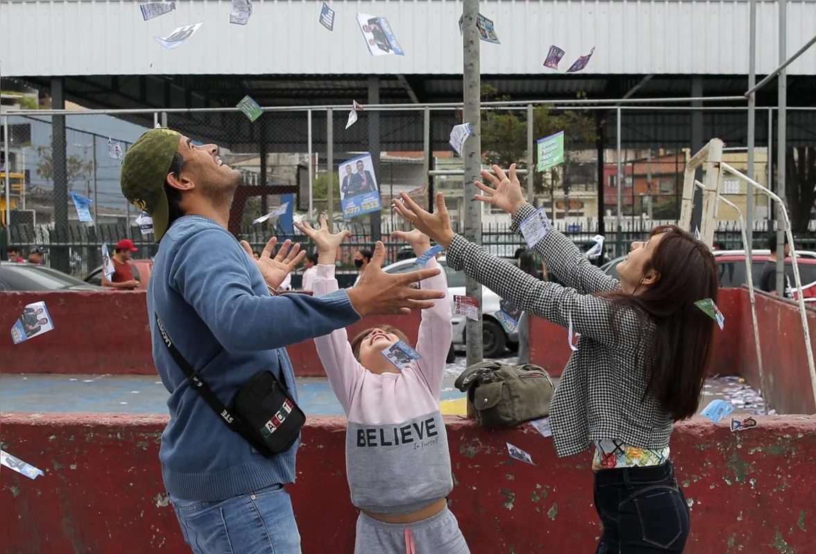 A couple and their daughter play with pamphlets during the legislative and presidential election, in Sao Paulo, Brazil, on October 2, 2022. - Voting began early Sunday in South America's biggest economy, plagued by gaping inequalities and violence, where voters ar expected to choose between far-right incumbent Jair Bolsonaro and leftist front-runner Luiz Inacio Lula da Silva, any of which must garner 50 percent of valid votes, plus one, to win in the first round. (Photo by CAIO GUATELLI / AFP)