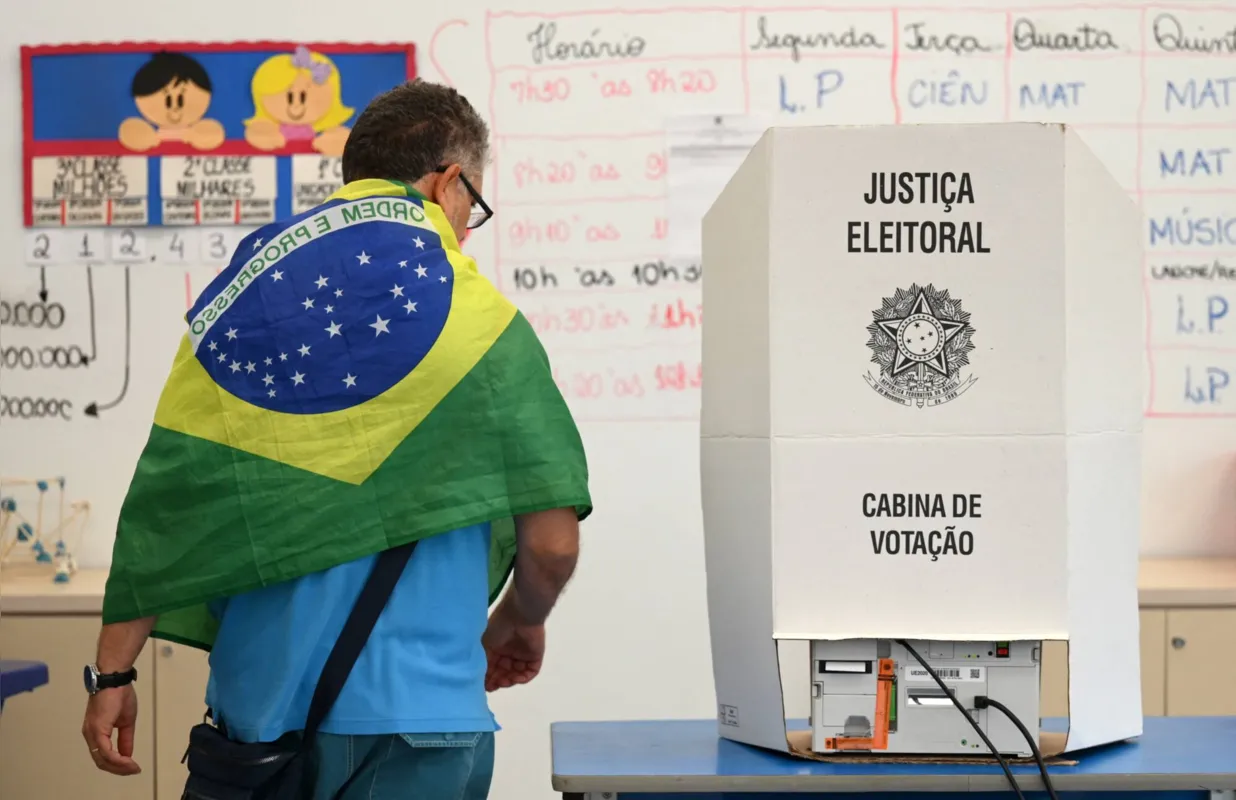 Com a bandeira nacional nas costas, eleitor de Bolsonaro vai à urna em Brasília